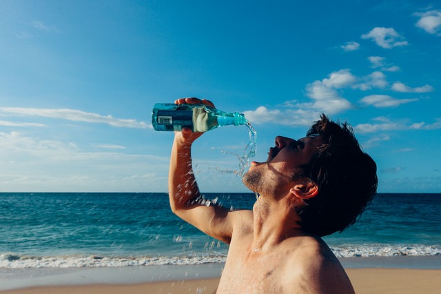 man drinking water on the beach